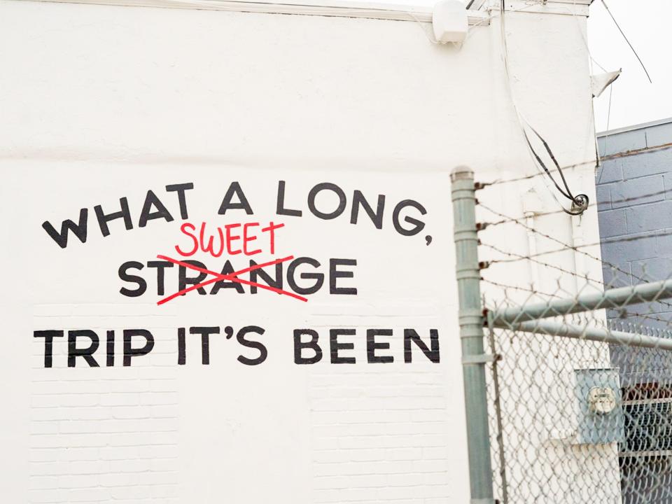 On the side of the building, a mural reads "What a long, sweet trip it's been."