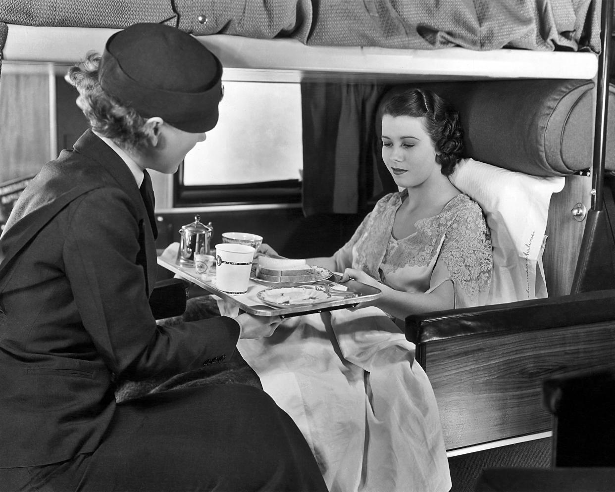 A flight attendant serves coffee and sandwiches to a passenger on board an American Airlines flight