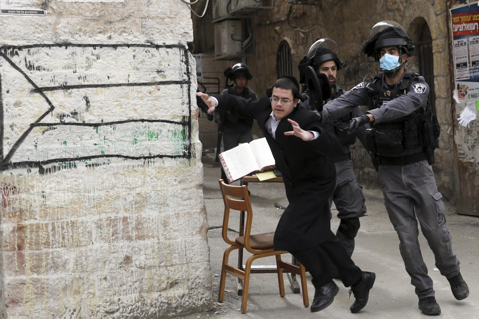 Policías empujan a un judío ultraortodoxo durante una protesta contra las medidas restrictivas del gobierno relacionadas con el coronavirus en Jerusalén el 30 de marzo del 2020. (AP Photo/Mahmoud Illean, File)