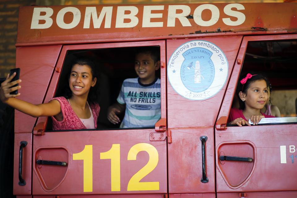 In this Jan. 13, 2019 photo, sons and daughters of firefighters take selfies inside the fire truck during a visit to the station in San Roque Gonzalez, Paraguay. Other members of the department also juggle firefighting with jobs as teachers, journalists or plumbers, while some still attend nursing school or are finishing a law degree. (AP Photo/Jorge Saenz)