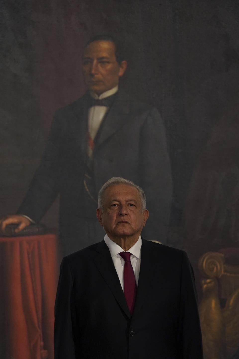 Mexican President Andres Manuel Lopez Obrador listens to his national anthem before giving his third state of the nation address at the National Palace in Mexico City, Wednesday, Sept. 1, 2021. Behind is a painting Mexico's first Indigenous President Benito Juarez. (AP Photo/Fernando Llano)