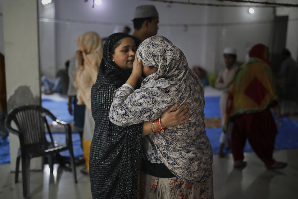 In this Friday, Feb. 28, 2020 photo, a woman comforts a neighbor inside a hall at Al-Hind hospital used as a shelter for people who were rescued after they were attacked by a Hindu mob, in Old Mustafabad neighborhood of New Delhi, India. On the eve of U.S. President Donald Trump’s first state visit to India last Sunday, Hindus and Muslims in the Indian capital charged at each other with homemade guns and crude weapons, leaving the streets where the rioting occurred resembling a war zone, with houses, shops, mosques, schools and vehicles up in flames, more than 40 dead and hundreds injured. (AP Photo/Altaf Qadri)