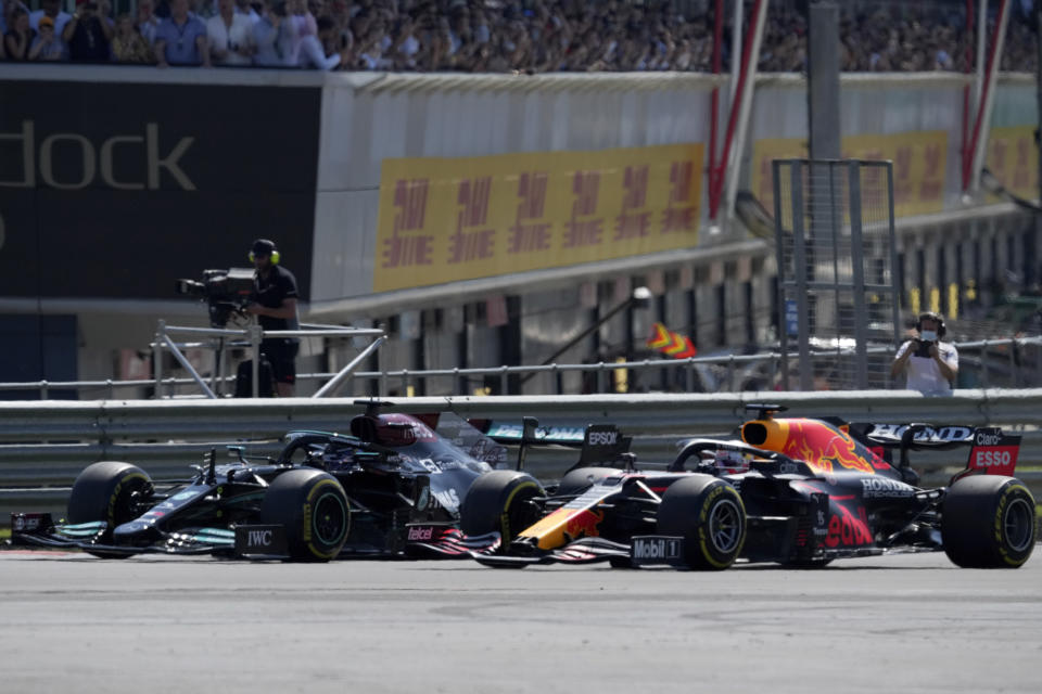 Mercedes driver Lewis Hamilton of Britain, left, and Red Bull driver Max Verstappen of the Netherlands take a curve side-by-side at the start of the British Formula One Grand Prix, at the Silverstone circuit, in Silverstone, England, Sunday, July 18, 2021. (AP Photo/Jon Super)