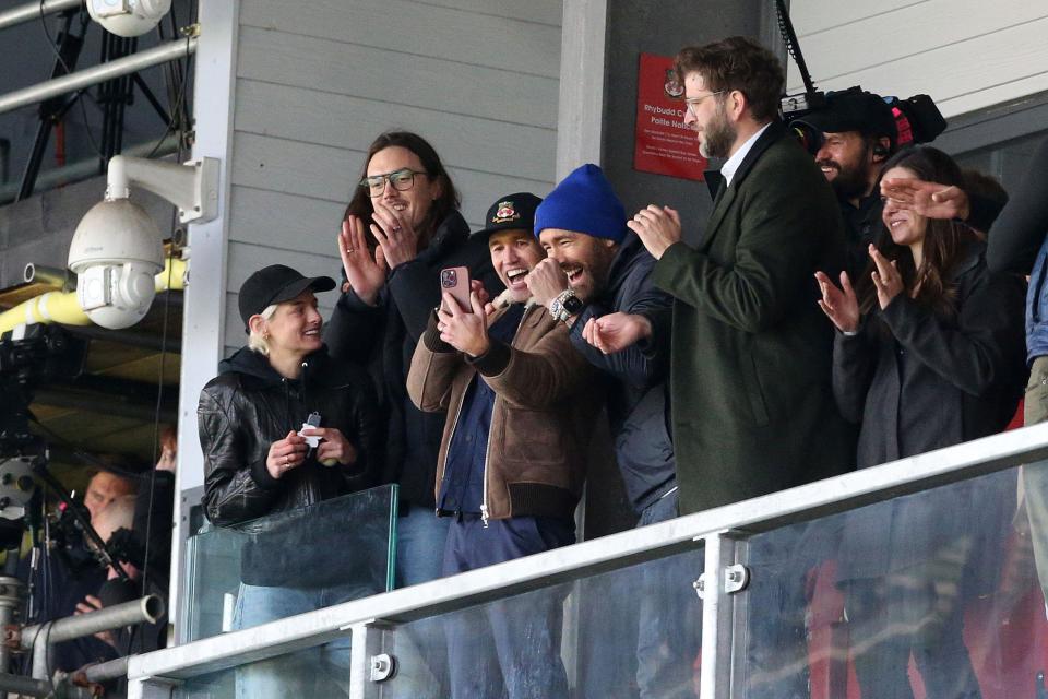 Wrexham owners Ryan Reynolds and Rob McElhenney and actress Emma Corrin (left) react during the Vanarama National League match at the Racecourse Ground, Wrexham. Picture date: Monday April 10, 2023.