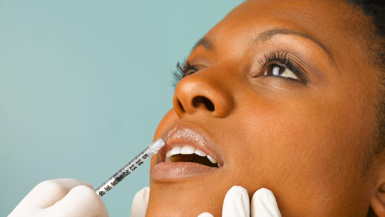 person injecting botox into woman's lip, close up, studio shot