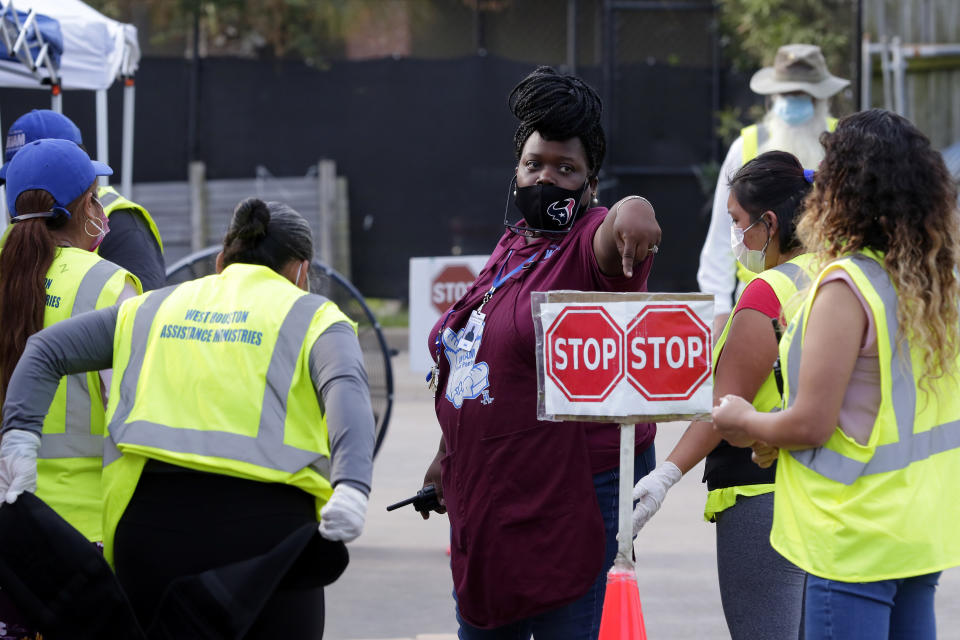 Diana Lindsey, center in purple, pantry assistant manager, gathers volunteers for last minute instructions before opening the drive thru food distribution line at the West Houston Assistance Ministries Wednesday, Oct. 14, 2020, in Houston. The charity was founded in 1982 to help people during an oil bust that eliminated 225,000 jobs and toppled the city's real estate market. The group also helps people pay their rent and find work. (AP Photo/Michael Wyke)