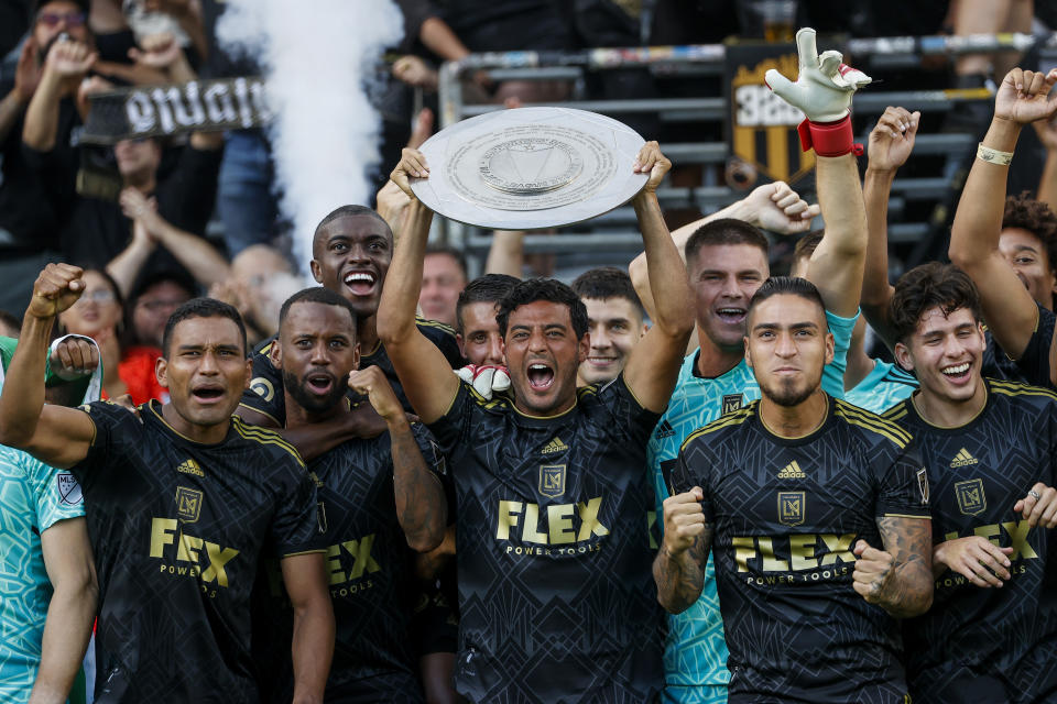 Los Angeles FC forward Carlos Vela, center, holds up the Supporters' Shield trophy in an awards ceremony after an MLS soccer match against the Nashville SC, Sunday Oct. 9, 2022, in Los Angeles. The Supporters' Shield is awarded to the MLS team with the best regular-season record. (AP Photo/Ringo H.W. Chiu)