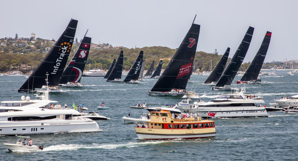 Competitors, back, race past spectators at the start of the 75th Sydney Hobart yacht race in Sydney Harbour, Thursday, Dec. 26, 2019. (Rolex/Carlo Borlenghi via AP)