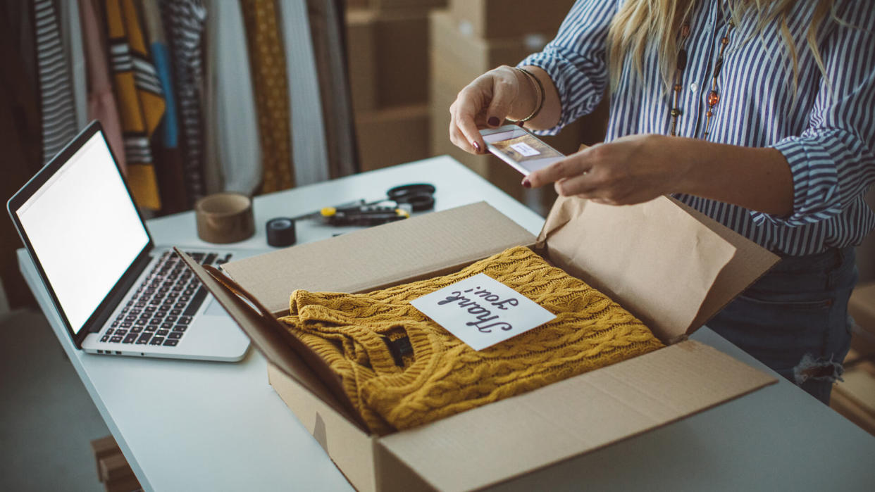 Women, owener of small business packing product in boxes, preparing it for delivery.