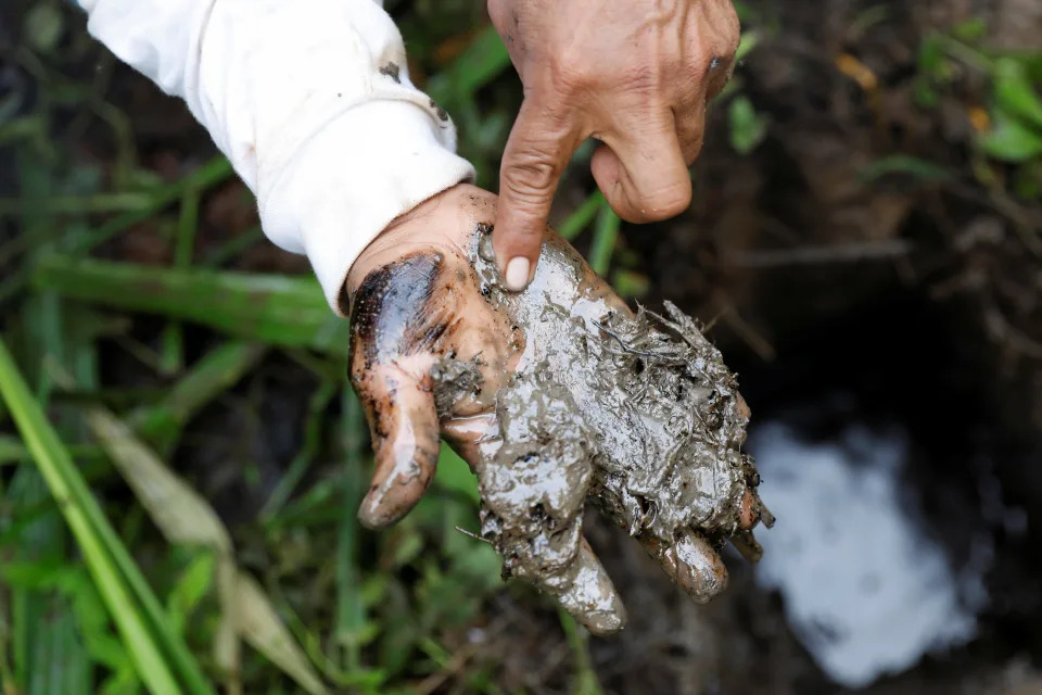 A man shows oil contamination inside Block 192, a dormant Amazon oil field in Peru.