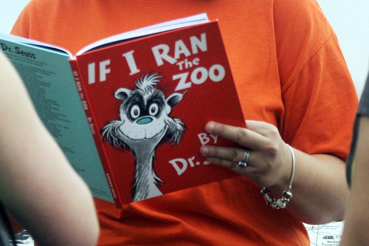 FILE - In this Sept. 24, 2013, file photo, a woman reads "If I Ran the Zoo," by Dr. Seuss. 