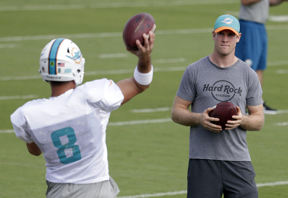 Miami Dolphins quarterback Ryan Tannehill, right, watches as quarterback Matt Moore (8) throws a pass during NFL football practice, Wednesday, Jan. 4, 2017 in Davie, Fla. Tannehill didn't take part in practice, making it unlikely he'll return from a left knee injury. The Dolphins play the Pittsburgh Steelers in an AFC Wild-Card game Sunday. (AP Photo/Lynne Sladky)