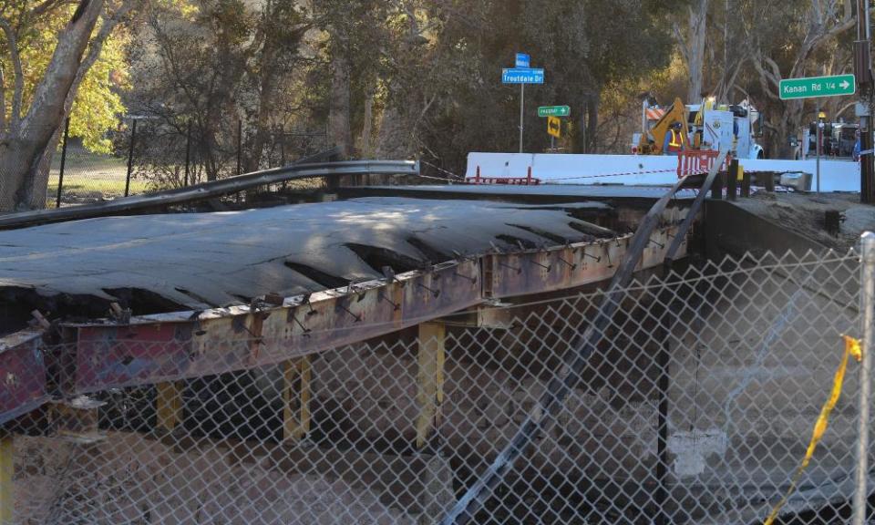 A worker looks on near a bridge destroyed by the heat from the Woolsey fire, in Cornell.