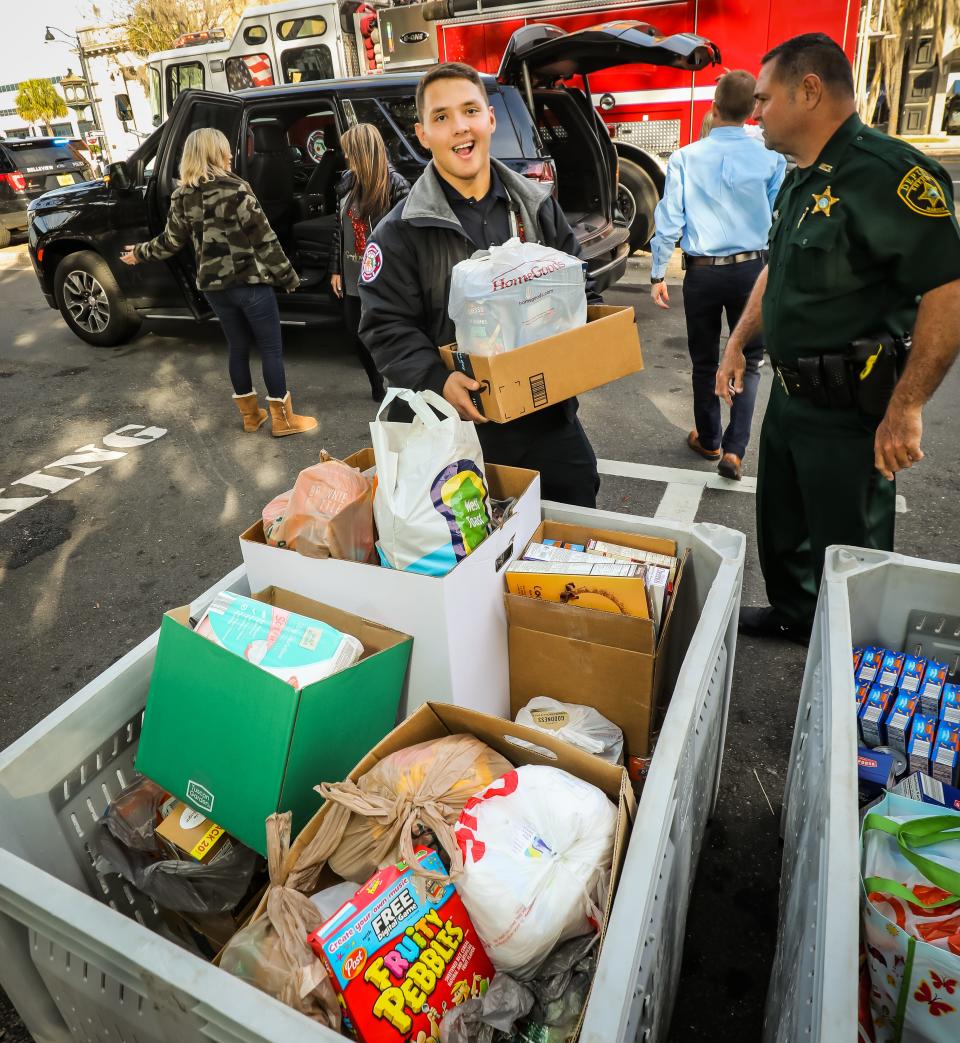 Marion County Fire Rescue firefighter Joshua Riddle helps unload a vehicle and fill a bin with canned and dry food goods on Friday during the Bring the Harvest Home food drive.