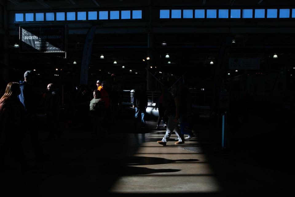 Attendees at the 42nd Ohio RV & Boat Show on Saturday walk through harsh light near the Buckeye Lake Marina display.