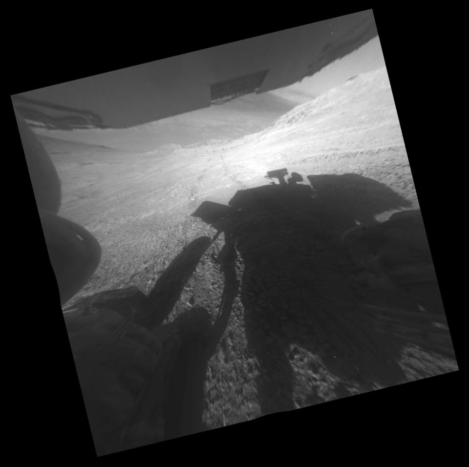 This March 22, 2016 photo made available by NASA shows the shadow and wheel tracks of the Mars Exploration Rover Opportunity just after a drive on a slope above Endeavour Crater. The image has been rotated 13.5 degrees to adjust for the tilt of the rover on a hillside. (NASA/JPL-Caltech via AP)