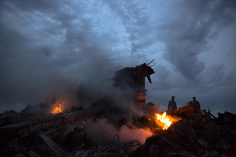FILE - In this Thursday, July 17, 2014 file photo, people walk amongst the debris at the crash site of a passenger plane near the village of Grabove, Ukraine. Five years after a missile blew Malaysia Airlines Flight 17 out of the sky above eastern Ukraine, relatives and friends of those killed are gathering Wednesday July 17, 2019, at a Dutch memorial to mark the anniversary. (AP Photo/Dmitry Lovetsky, file)