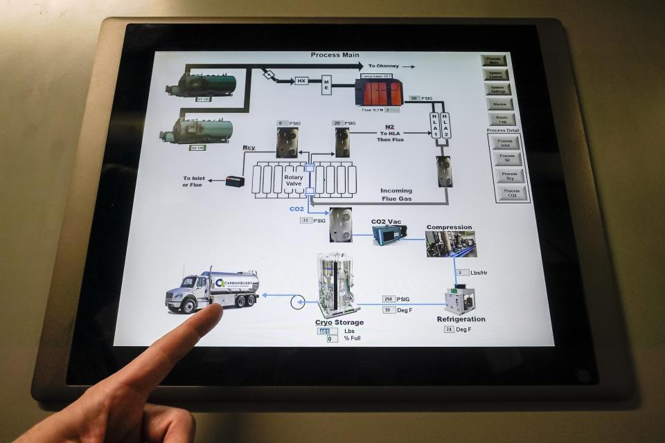 Brian Asparro, chief operating officer of CarbonQuest, points to a delivery truck on a touch screen display outlining the process from which liquid carbon dioxide is produced as a byproduct of a natural gas fired water boiler in the basement of The Grand Tier luxury apartment building, Tuesday, April 18, 2023, in New York. New York is forcing buildings to clean up, and several are experimenting with capturing the carbon dioxide, cooling it into a liquid and mixing it into concrete where it turns into a mineral. (AP Photo/John Minchillo)