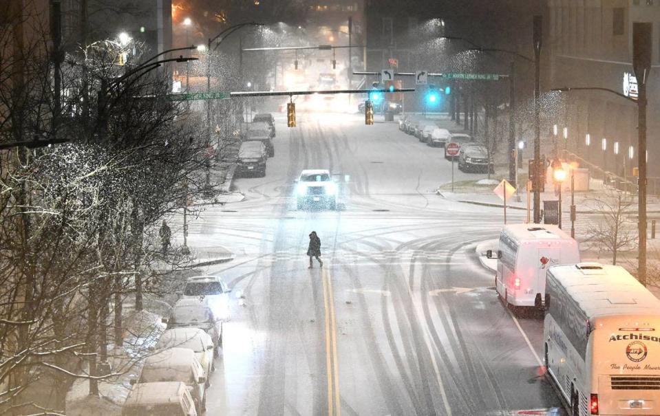 A pedestrian crosses Brevard Street as snow falls in uptown Charlotte, NC on Friday, January 21, 2022.