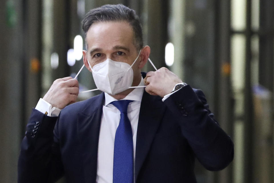 German Foreign Minister Heiko Maas prepares to take off his protective face mask as he arrives for a meeting of EU foreign ministers at the European Council building in Brussels, Monday, Feb 22, 2021. European Union foreign ministers on Monday will look at options for imposing fresh sanctions against Russia over the jailing of opposition leader Alexei Navalny as the 27-nation bloc considers the future of its troubled ties with the country. (Yves Herman, Pool via AP)