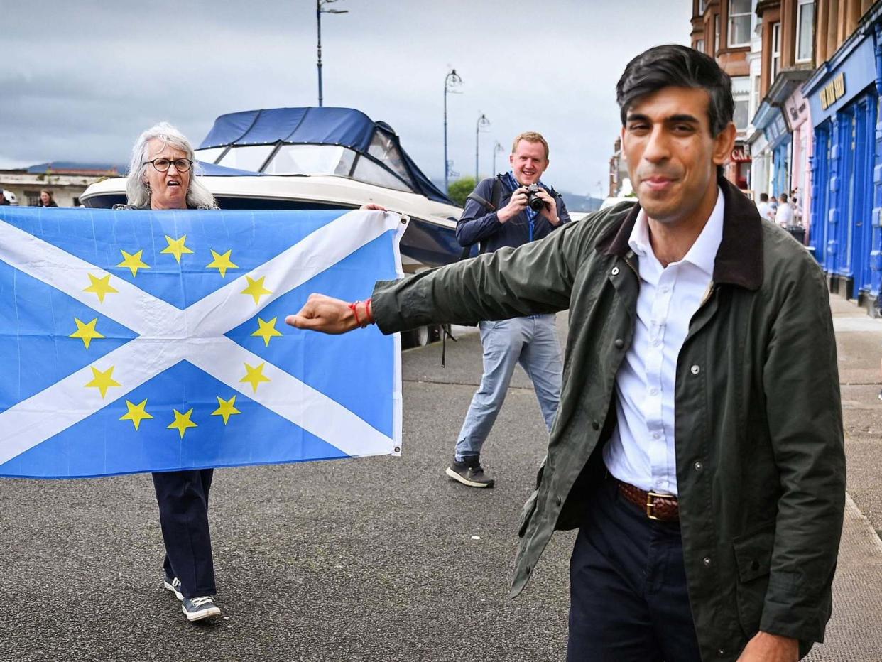 A pro-independence demonstrator holds a flag as she welcomes chancellor Rishi Sunak to Scotland: REUTERS