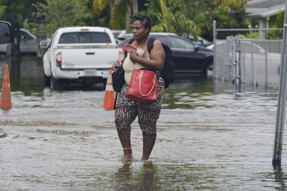 A woman walks with her belongings on a flooded street, Thursday, June 13, 2024, in North Miami, Fla. Over 20 inches of rain fell over two days was in North Miami. A tropical disturbance has brought a rare flash flood emergency to much of southern Florida. Floridians prepared to weather more heavy rainfall on Thursday and Friday. (AP Photo/Marta Lavandier)