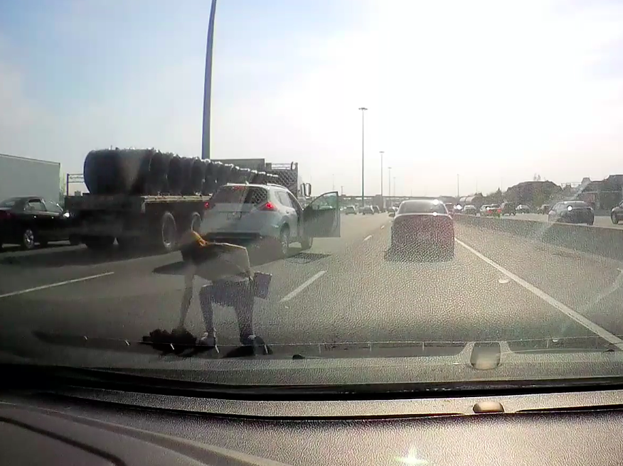 A woman gets to her feet after tumbling from a moving SUV on Highway 401 on May 14.