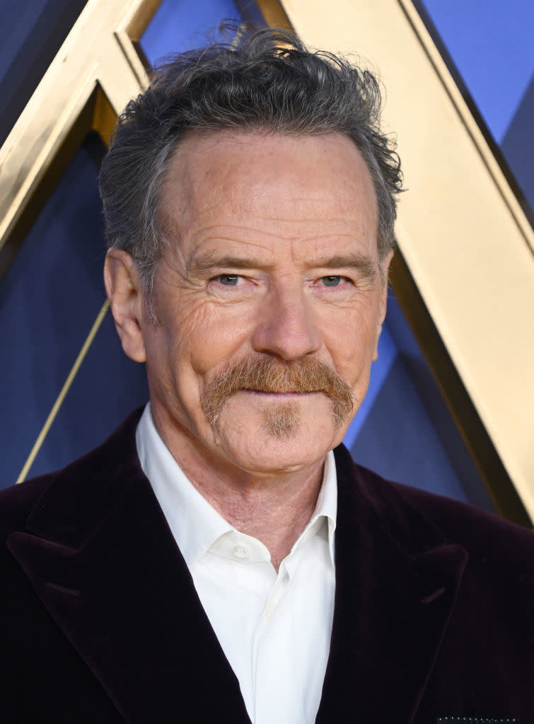 closeup of bryan with a mustache and beard in a velvet suit smiling at an event