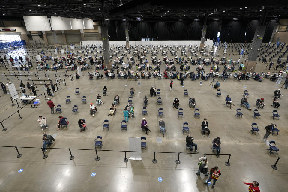 People sit in chairs in an observation area, Saturday, March 13, 2021, after getting shots of the Pfizer COVID-19 vaccine on the first day of operations at a mass vaccination site at the Lumen Field Events Center in Seattle, which adjoins the field where the NFL football Seattle Seahawks and the MLS soccer Seattle Sounders play their games. The site, which is the largest civilian-run vaccination site in the country, will operate only a few days a week until city and county officials can get more doses of the vaccine. (AP Photo/Ted S. Warren)