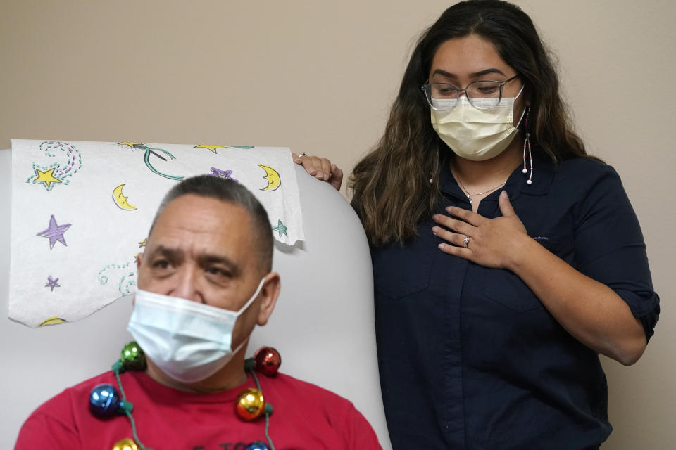 Lummi Nation member James Scott (native name Qwelexwbed), left, waits to receive the first COVID-19 vaccination on the Lummi Reservation as his granddaughter, Mackayla Alvarez, the family's oral historian, looks on to witness the moment, Thursday, Dec. 17, 2020, near Bellingham, Wash. The Native American tribe began rationing its first 300 doses of vaccine as it fights surging cases with a shelter-in-place order. (AP Photo/Elaine Thompson)