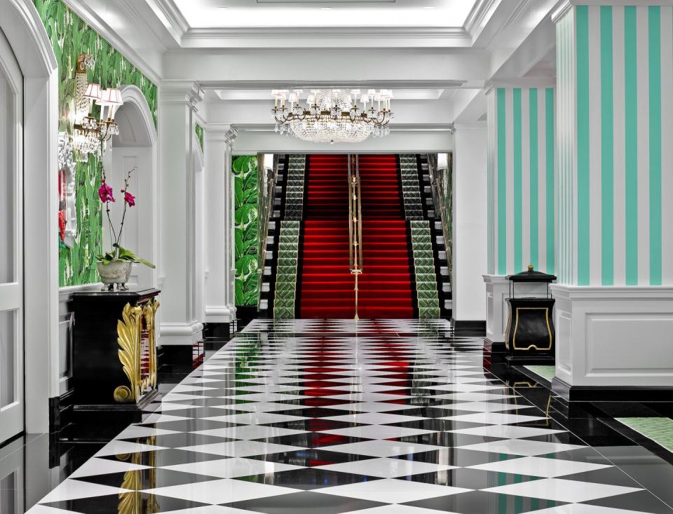 a room with a fireplace and a door with a red door with the greenbrier in the background