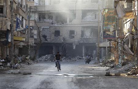 A man rides his bicycle on a damaged street in Deir al-Zor August 30, 2013. Picture taken August 30, 2013. REUTERS/Khalil Ashawi