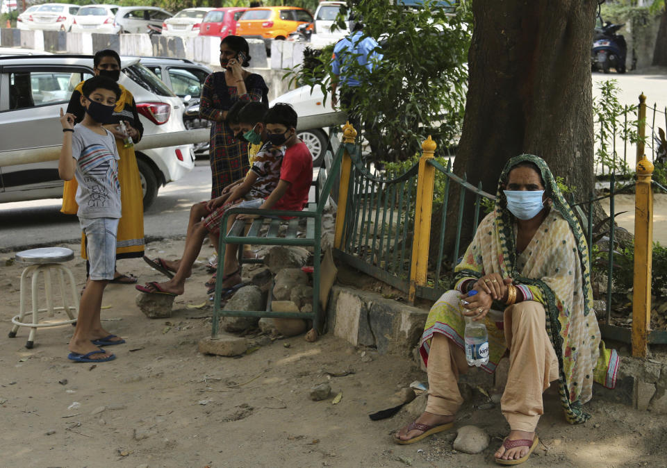 Indians wearing face masks wait to consult doctors outside a COVID-19 screening facility at a government run hospital in Jammu, Saturday, June 27, 2020. India is the fourth hardest-hit country by the pandemic in the world after the U.S., Russia and Brazil. (AP Photo/Channi Anand)