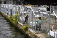 FILE - In this Monday, June 1, 2020 file photo, customers seated in small glasshouses enjoy lunch at the Mediamatic restaurant in Amsterdam, Netherlands. The coronavirus pandemic is gathering strength again in Europe and, with winter coming, its restaurant industry is struggling. The spring lockdowns were already devastating for many, and now a new set restrictions is dealing a second blow. Some governments have ordered restaurants closed; others have imposed restrictions curtailing how they operate. (AP Photo/Peter Dejong, File)