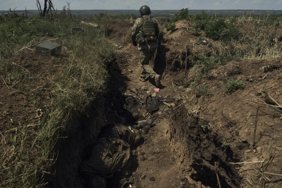FILE - A Ukrainian soldier goes in a recently captured Russian trench with dead Russian soldiers, on the frontline near Bakhmut, Donetsk region, Ukraine, Tuesday, July 4 2023. Ukrainian forces are making steady progress along the northern and southern flanks of Bakhmut, in a semi-encirclement of the wrecked city that Russian forces have been occupying since May. (AP photo/Libkos, File)