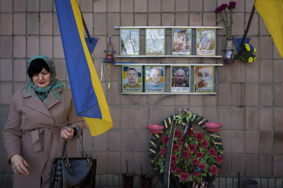 Nataliia Verbova, wife of Andrii Verbovyi, in the top left picture, one of eight men killed by Russian forces near the building on Yablunska street, leaves after lighting a candle at the place where her husband's body was abandoned, in Bucha, Ukraine, Tuesday, March 26, 2024. Days after Russian forces withdrew from the area in late March, in the dramatic first weeks of the full-scale invasion, a photo taken by AP Photographer Vadim Ghirda revealed what happened to the eight men. (AP Photo/Vadim Ghirda)