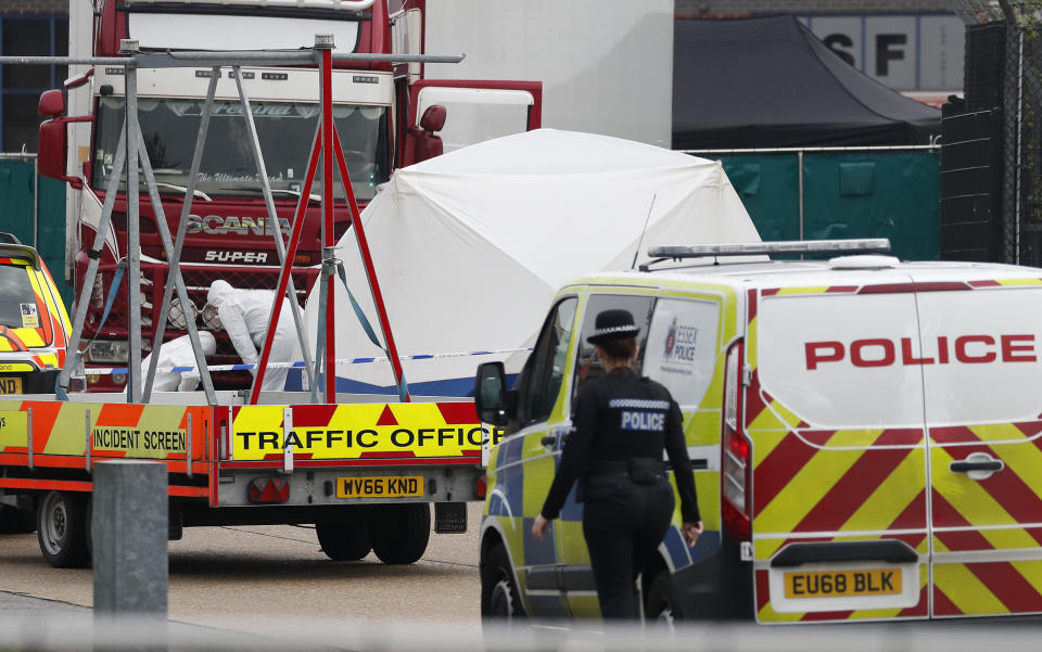 Police forensic officers attend the scene after a truck, in rear, was found to contain a large number of dead bodies, in Thurrock, South England, early Wednesday Oct. 23, 2019. Police in southeastern England said that 39 people were found dead Wednesday inside a truck container believed to have come from Bulgaria. (AP Photo/Alastair Grant)