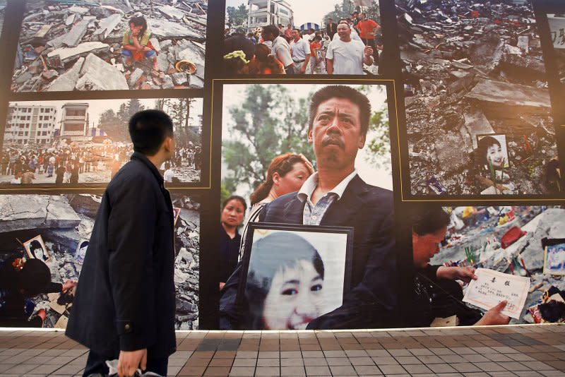 A man stops to look at a sidewalk photography exhibit of images taken after the killer May 12, 2008, earthquake hit Sichuan, in Beijing January 14, 2009. File Photo by Stephen Shaver/UPI