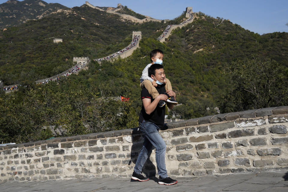 A man carries a child up a stretch of the Badaling Great Wall of China on the outskirts of Beijing on Tuesday, Oct. 6, 2020. Chinese tourists took 425 million domestic trips in the first half of the eight-day National Day holiday, generating $45.9 billion in tourism revenue, according to China's ministry of culture and tourism. The holiday this year, which coincides with the Mid-Autumn Festival, will be a litmus test of whether China's tourism industry can bounce back after being battered by COVID-19. (AP Photo/Ng Han Guan)