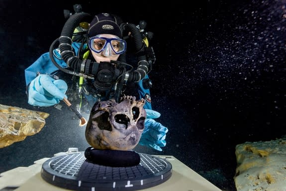 Diver Susan Bird working at the bottom of Hoyo Negro, a large dome-shaped underwater cave on Mexico's Yucatan Peninsula. She carefully brushes the human skull found at the site while her team members take detailed photographs.