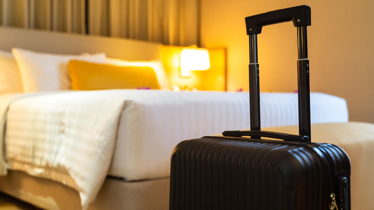  Suitcase next to a hotel bed. 