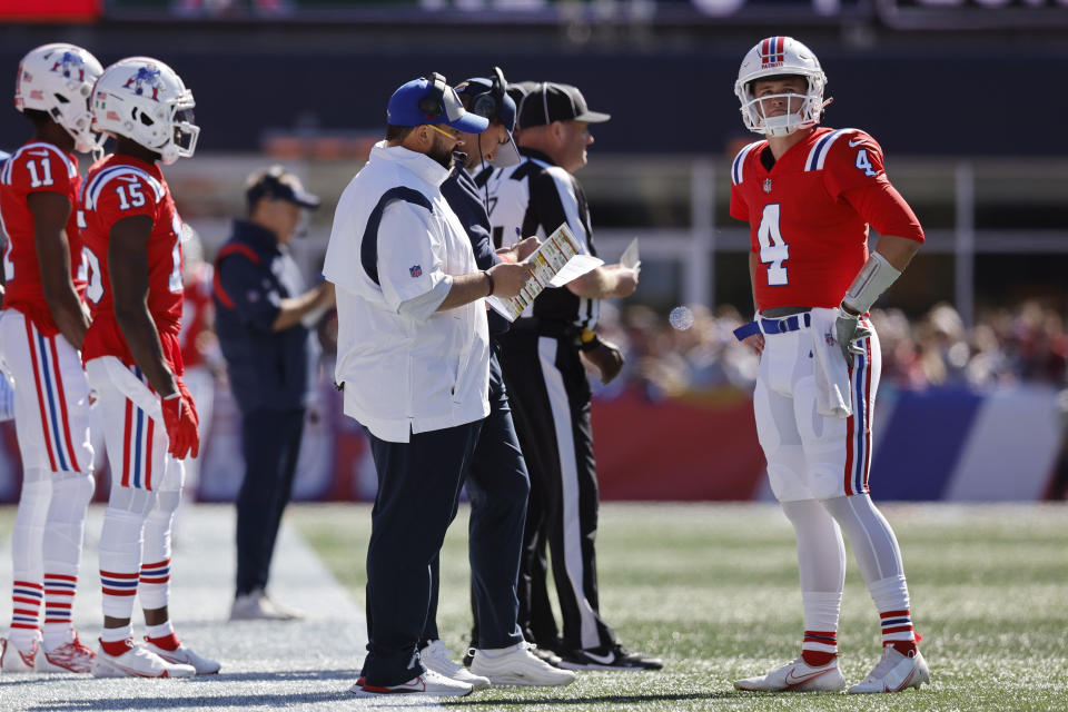 New England Patriots quarterback Bailey Zappe (4) speaks with Patriots senior football advisor/offensive line Matt Patricia, center left, during the first half of an NFL football game against the Detroit Lions, Sunday, Oct. 9, 2022, in Foxborough, Mass. (AP Photo/Michael Dwyer)