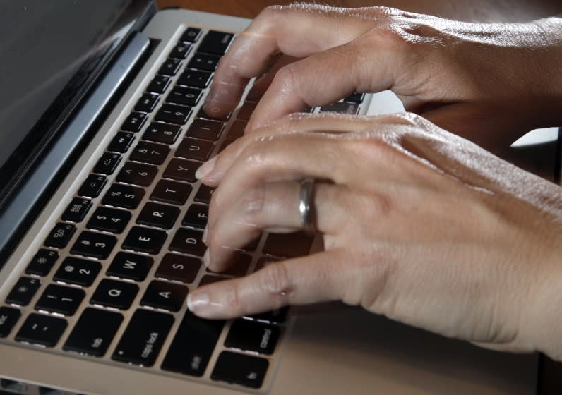 In this Monday, June 19, 2017, photo, a person types on a laptop keyboard, in North Andover, Mass. One of the nation's biggest telemedicine providers is spending more than $18 billion to stoke an approach to care that grew explosively during the pandemic. Teladoc Health plans to dive deep into managing the health of patients with diabetes and high blood pressure with a cash-and-stock deal for Livongo Health. Telemedicine involves care delivered remotely, often with a live video connection through patient smartphones or tablets. (AP Photo/Elise Amendola)