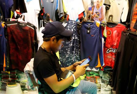 A vendor uses a mobile phone to surf internet at a clothes shop in Paranaque, Metro Manila, Philippines July 7, 2016. Picture taken July 7, 2016. REUTERS/Erik De Castro