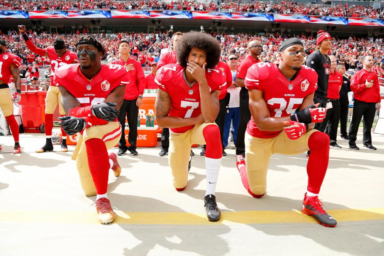Colin Kaepernick kneels during the national anthem with fellow San Francisco 49ers Eli Harold and Eric Reid: EPA