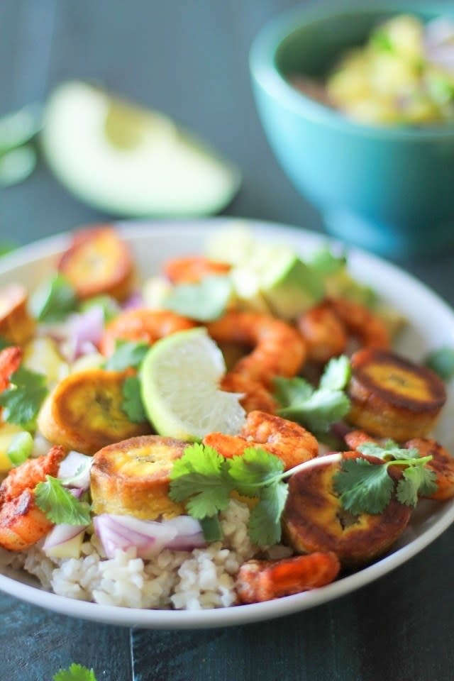 A close=up view of a coconut rice bowl topped with shrimp, mango slaw, and plantains.