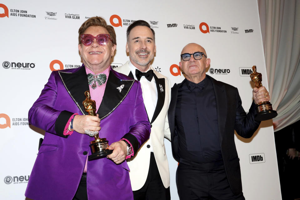 Elton John, from left, David Furnish, and Bernie Taupin celebrate Elton John and Bernie Taupin winning an Academy Award as they arrive at the 2020 Elton John AIDS Foundation Oscar Viewing Party on Sunday, Feb. 9, 2020, in West Hollywood, Calif. (Photo by Willy Sanjuan/Invision/AP)