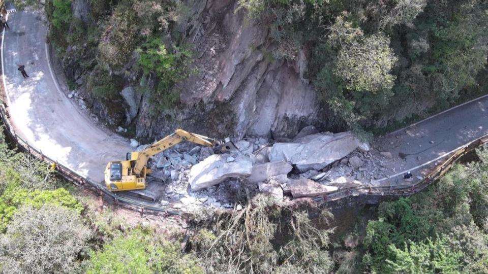 從山壁落下的巨石阻斷了整個道路，工務段人員操作怪手試圖清理落石。（圖／翻攝自公路局：公路人臉書）