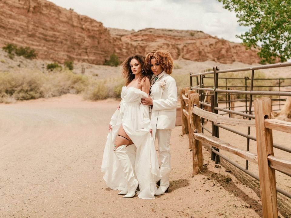 Two brides embrace in a desert.