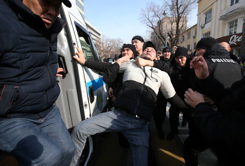 Kazakh law enforcement officers detain a protester during a rally held by opposition supporters in Almaty